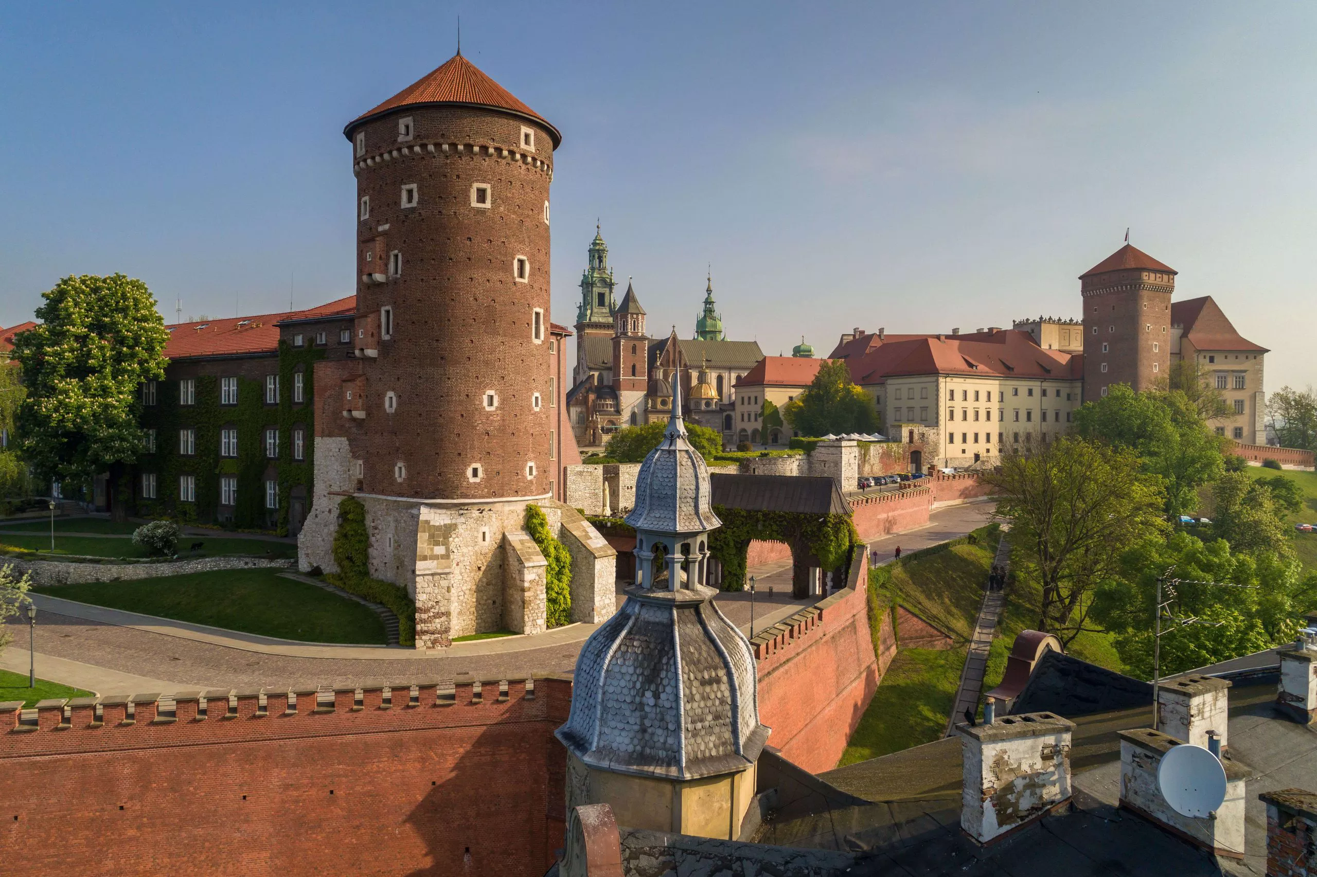 Das Foto zeigt einen Teil des Schlossgebäudes aus der Vogelperspektive. Im Vordergrund ist ein runder Turm zu sehen und im Hintergrund die Kathedrale