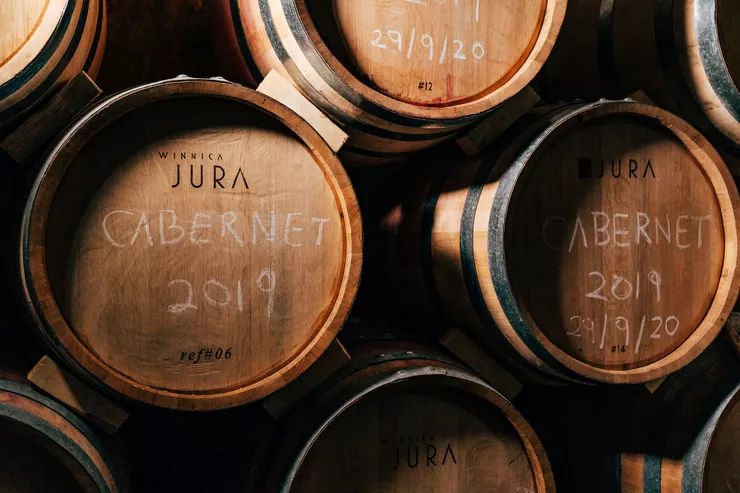 A view of the barrels of wine arranged into rows. Their heads bear the name of the vineyard, and chalked names of grape variety and dates.