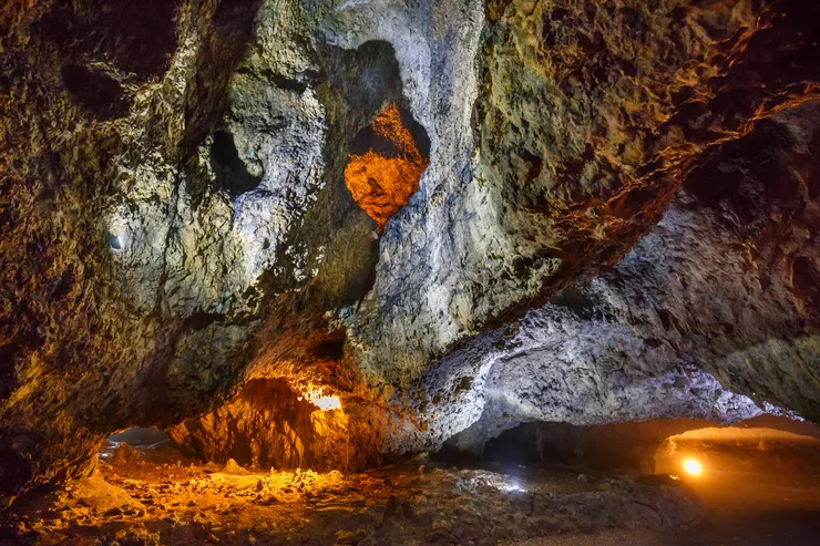 Ein Blick auf das felsige Innere der Höhle. An einigen Stellen ist orangefarbenes Licht zu sehen.